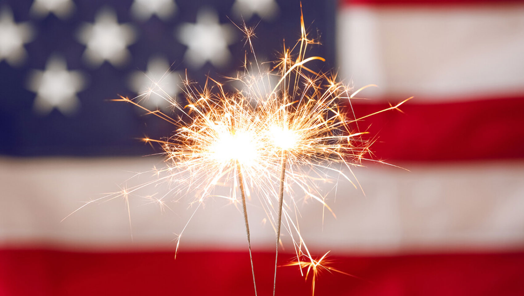 Small fireworks glowing in front of an American flag