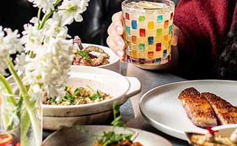 and holding cocktail + food items on set table