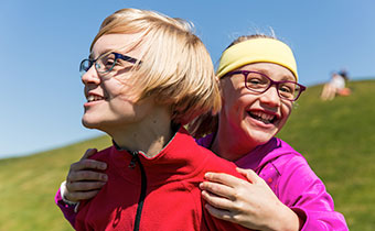 two people walking down a grassy hill